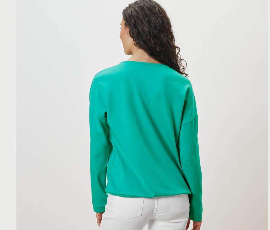 Zezadu pohled na ženu s tmavými vlasy v modrozelené mikině.