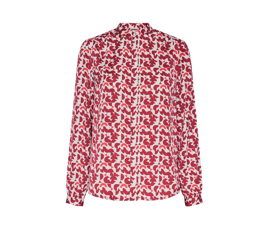 Detail dámské halenky s červeným geometrickým potiskem.