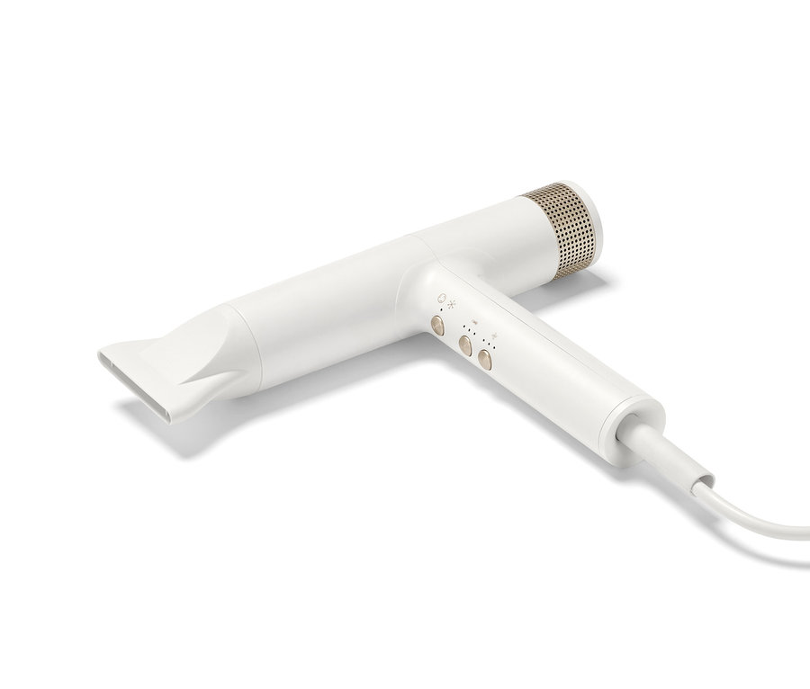 Bílý prémiový vysoušeč vlasů s novou technologií sušení leží na bílém pozadí.