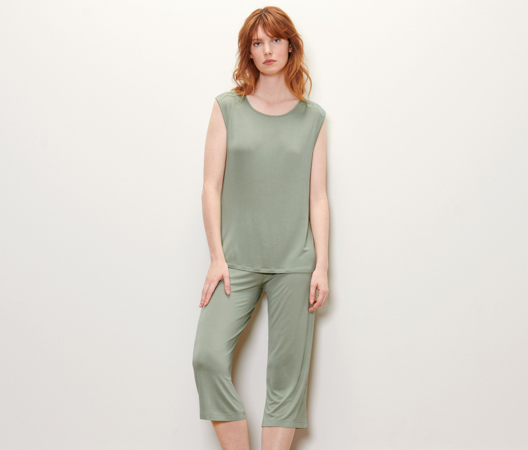 Žena pózuje v zeleném pyžamu.