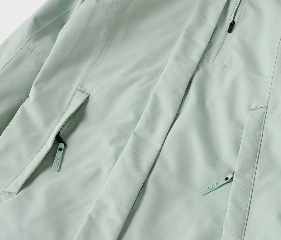 Detail světle zelené bundy s kapsami na zip.