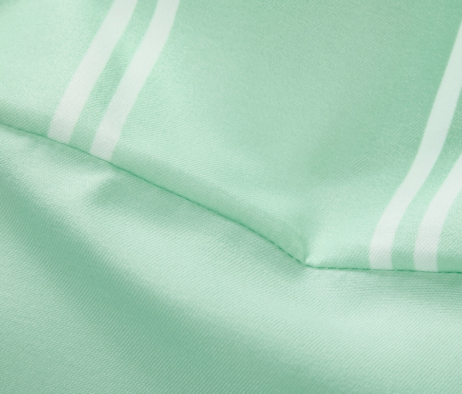 Detail světle zelené látky s bílými pruhy.