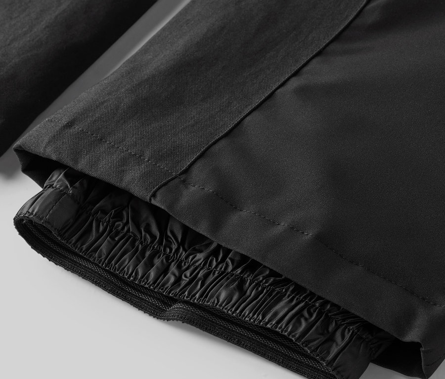 Detail černých kalhot se stahovací gumou u kotníků.