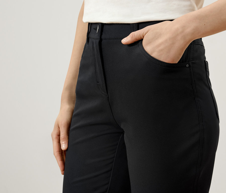 Žena má ruku v kapse černých kalhot.