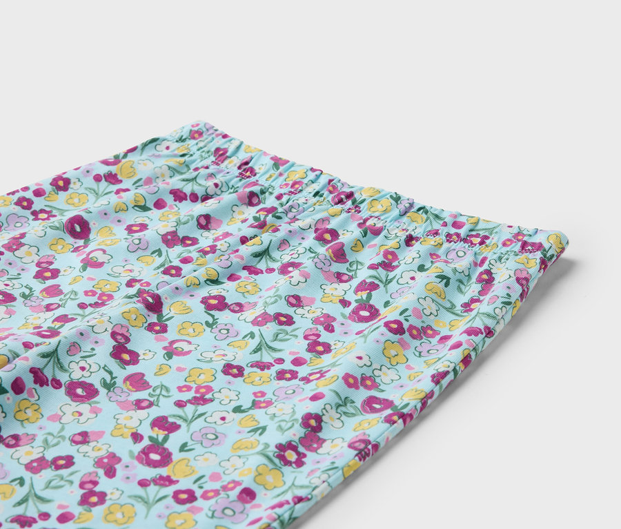 Detail světle modrých kalhot s květinovým vzorem a elastickým pasem.