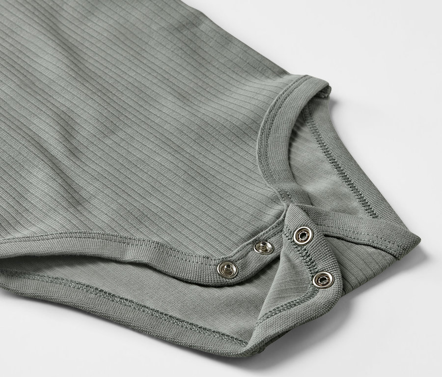 Detail šedého žebrovaného body s dlouhým rukávem pro miminka se zapínáním na patentky.