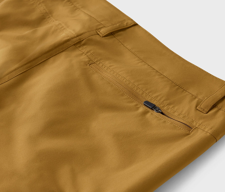 Detailní záběr na khaki kalhoty s částečně otevřeným zipem na kapse.