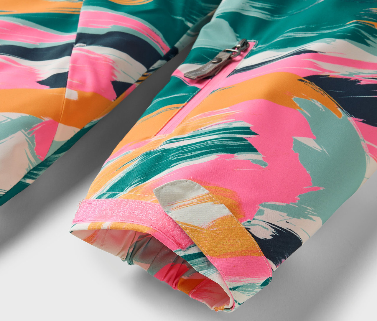 Detail barevné bundy s abstraktním vzorem.