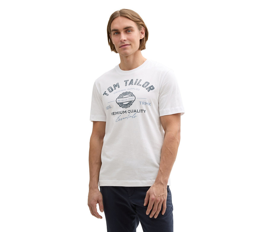 Muž má na sobě bílé tričko Tom Tailor s logem.