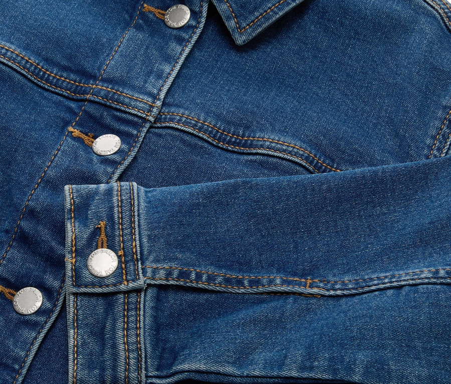Detail modré džínové bundy se stříbrnými knoflíky.