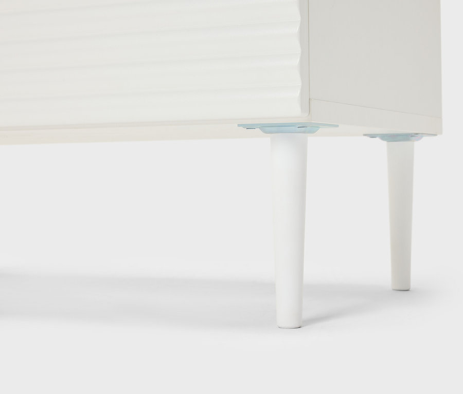 Detailní pohled na bílý nábytek s kónickými nohami.