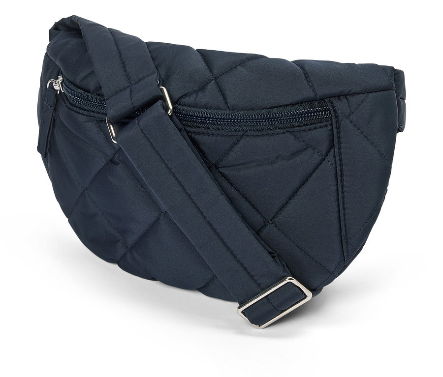 Detailní záběr na tmavě modrou, prošívanou ledvinku se stříbrnými zipy a nastavitelným popruhem na bílém pozadí.