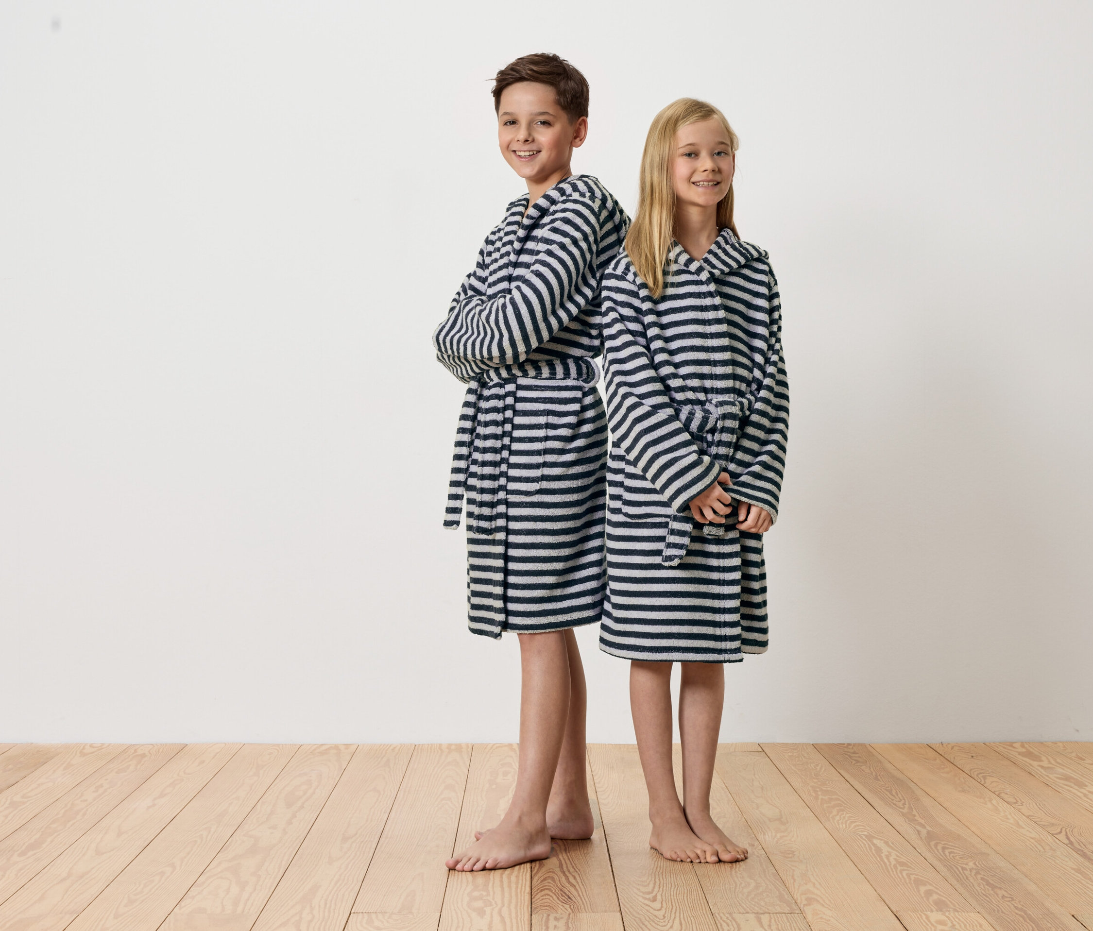 Chlapec a dívka stojí zády k sobě a mají na sobě pruhované župany.