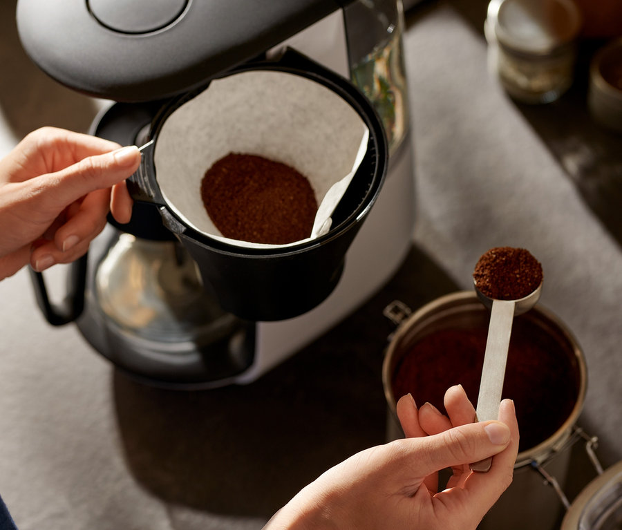 Žena přidává kávu do bílého překapávače »Let's Brew«.