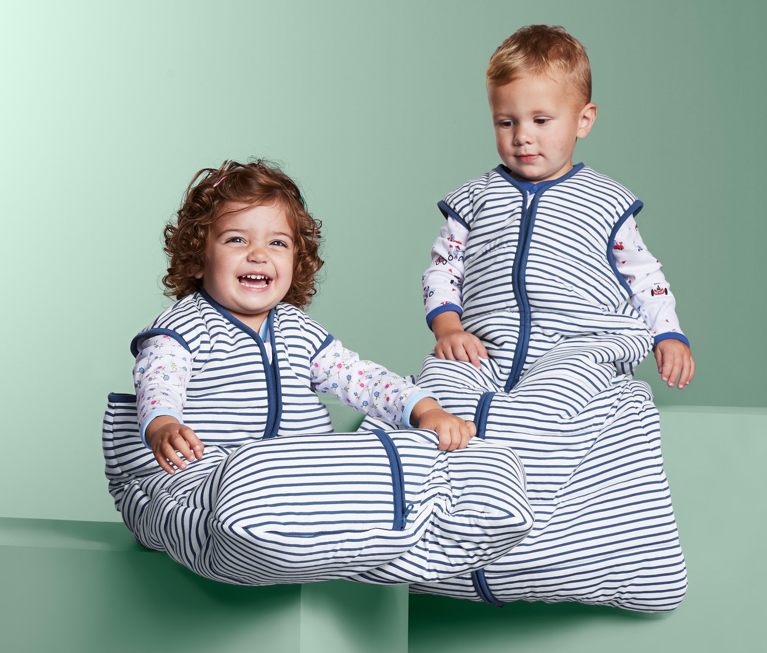 Děti sedí na blocích v pruzích spacích pytlích.