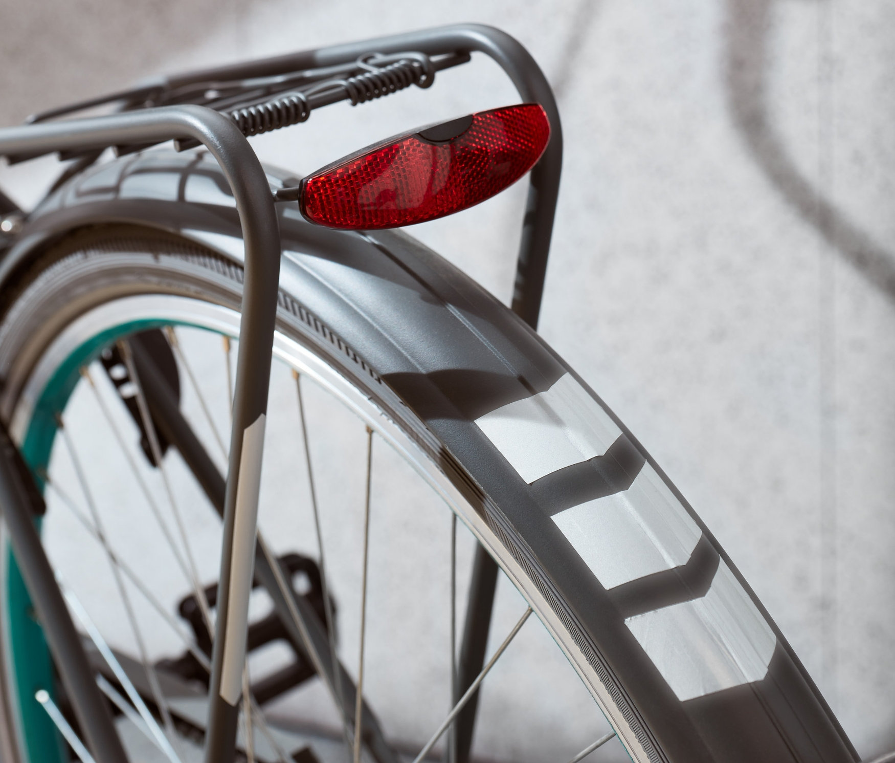 Detail zadního kola jízdního kola s červeným světlem a reflexními nálepkami.