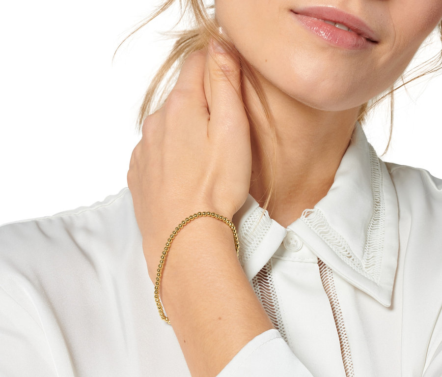 Blondýna se dotýká krku a na zápěstí má sadu náramků »Happy«.