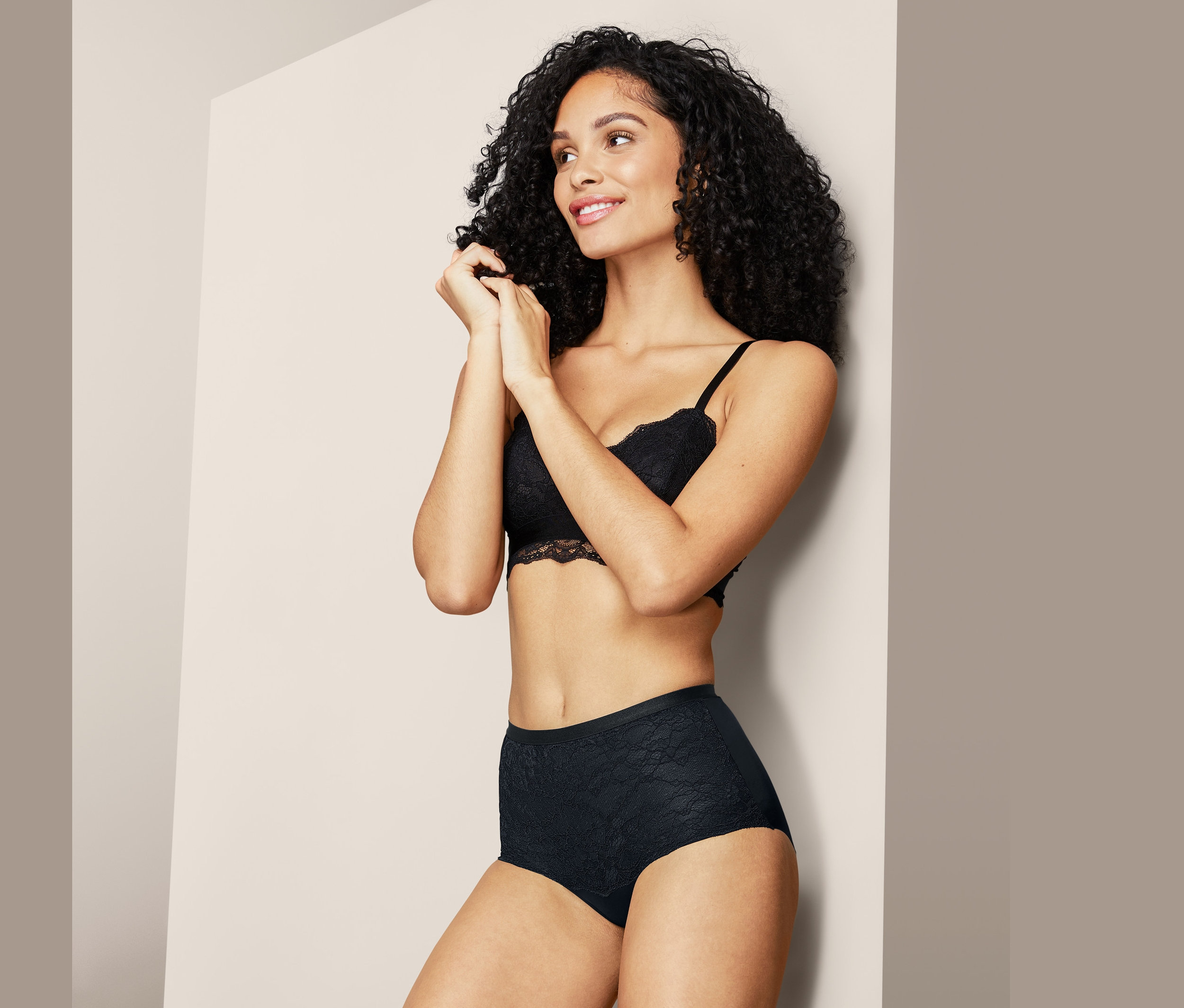 Žena pózuje v černé krajkové podprsence a stahovacích kalhotkách.