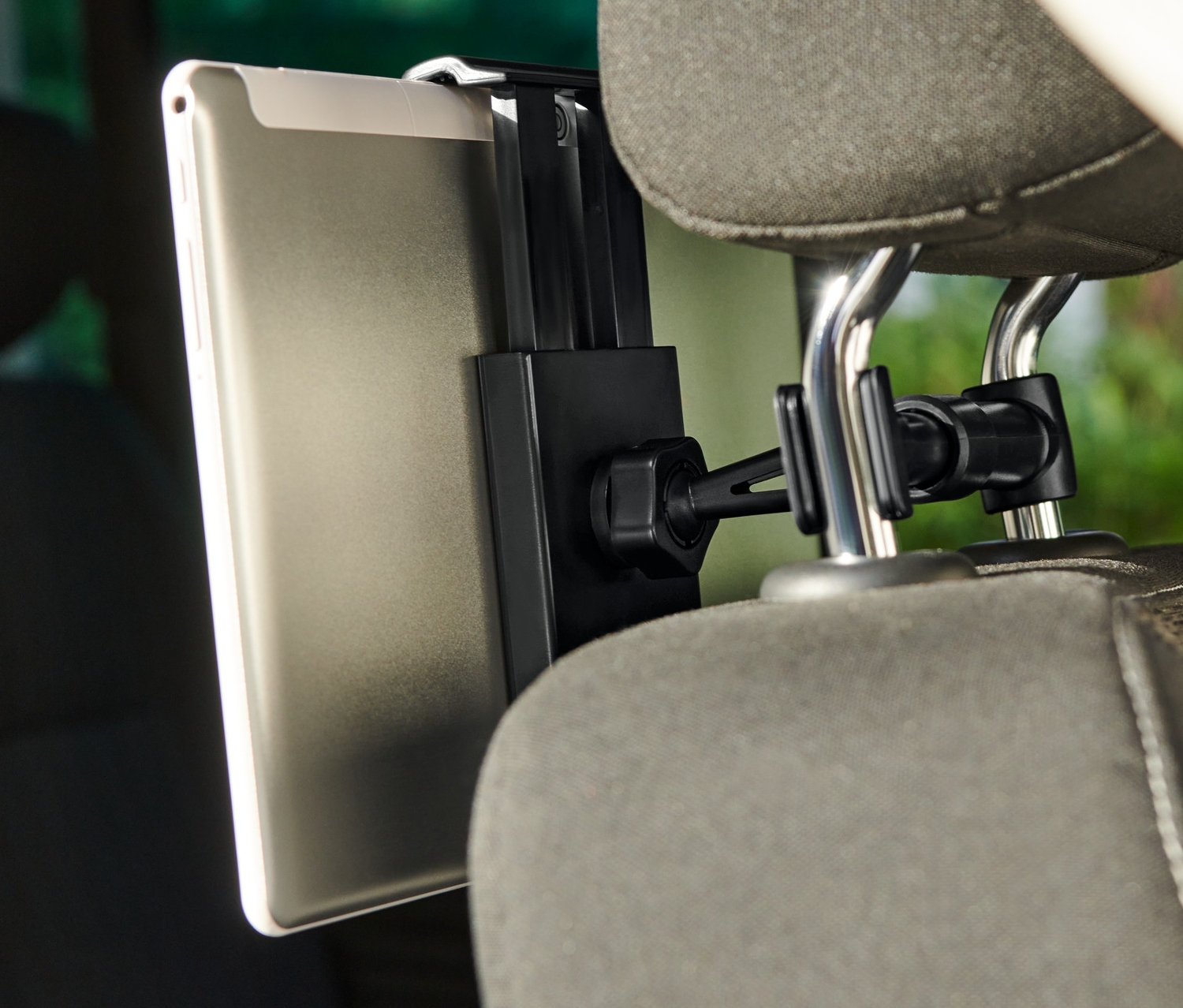 Tablet připevněný k držáku na tablet do auta, který je upevněný na opěrce hlavy sedadla.