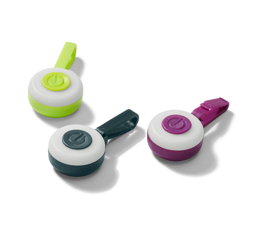 Tři LED přívěsky v zelené, tmavě modré a fialové barvě leží na bílém povrchu.