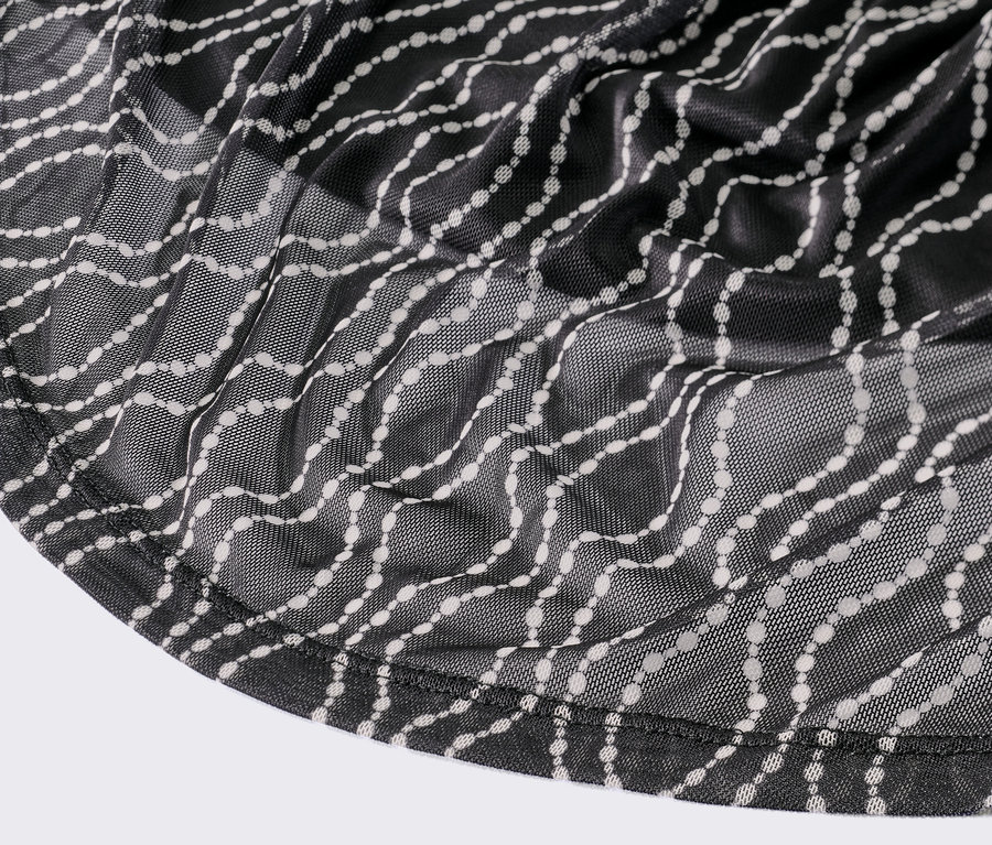 Detail černých síťovaných šatů s potiskem.