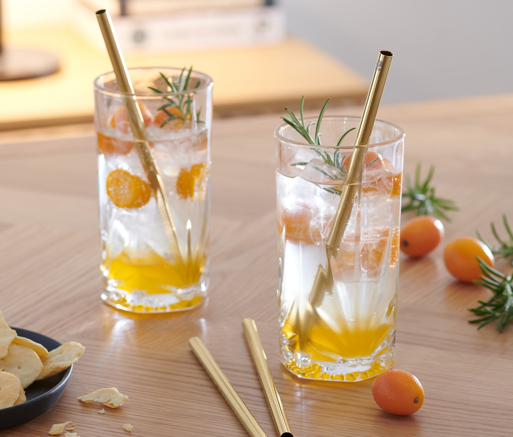 Dva nápoje s plátky ovoce a kovovými brčky, 4 ks, na dřevěném stole.