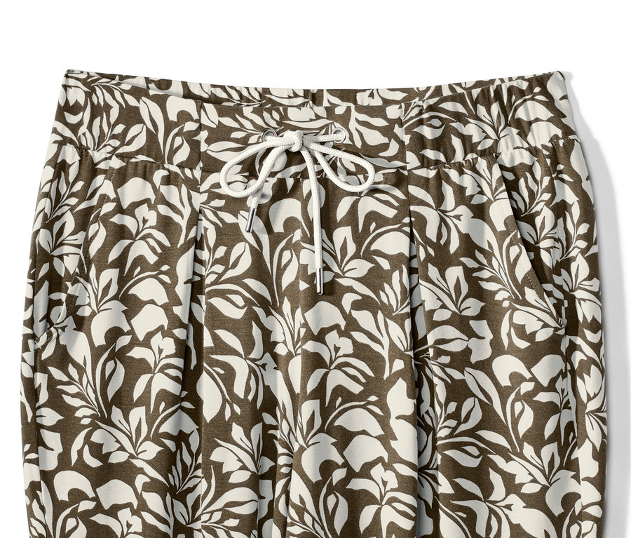 Detail žerzejových kalhot s potiskem listů a stahovací šňůrkou v pase.