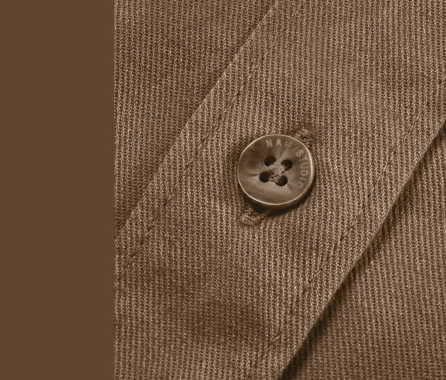 Detail hnědé lněné košile s knoflíkem.