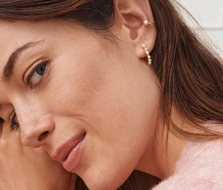 Portrét ženy s kruhovými náušnicemi s umělými perlami a náušnicemi Earcuff s uměle pěstovanými sladkovodními perlami.