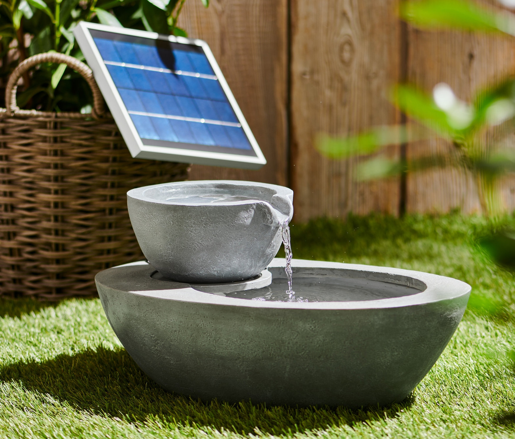 Šedá solární zahradní fontána se dvěma miskami na trávě.