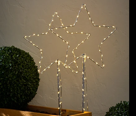 Dva velké LED bodce k zapíchnutí do země ve tvaru hvězdy umístěné v dřevěném květináči.