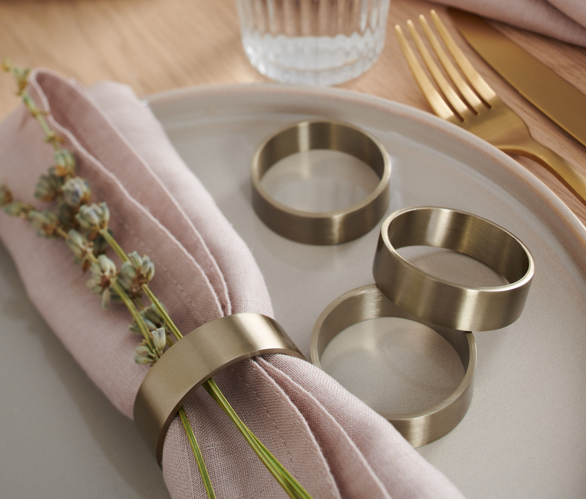 Na talíři leží růžový ubrousek s dekorací a kroužkem na ubrousky, 4 ks. Dále jsou zde tři kroužky na ubrousky.