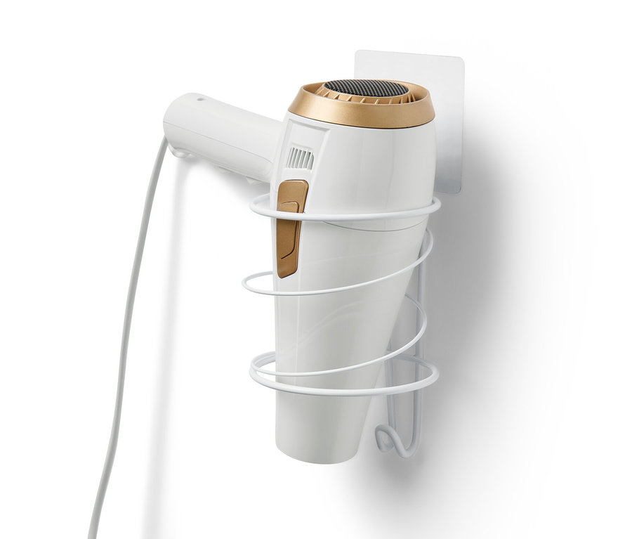 Bílý držák na vysoušeč vlasů je připevněn na bílé zdi a drží bílý vysoušeč vlasů.