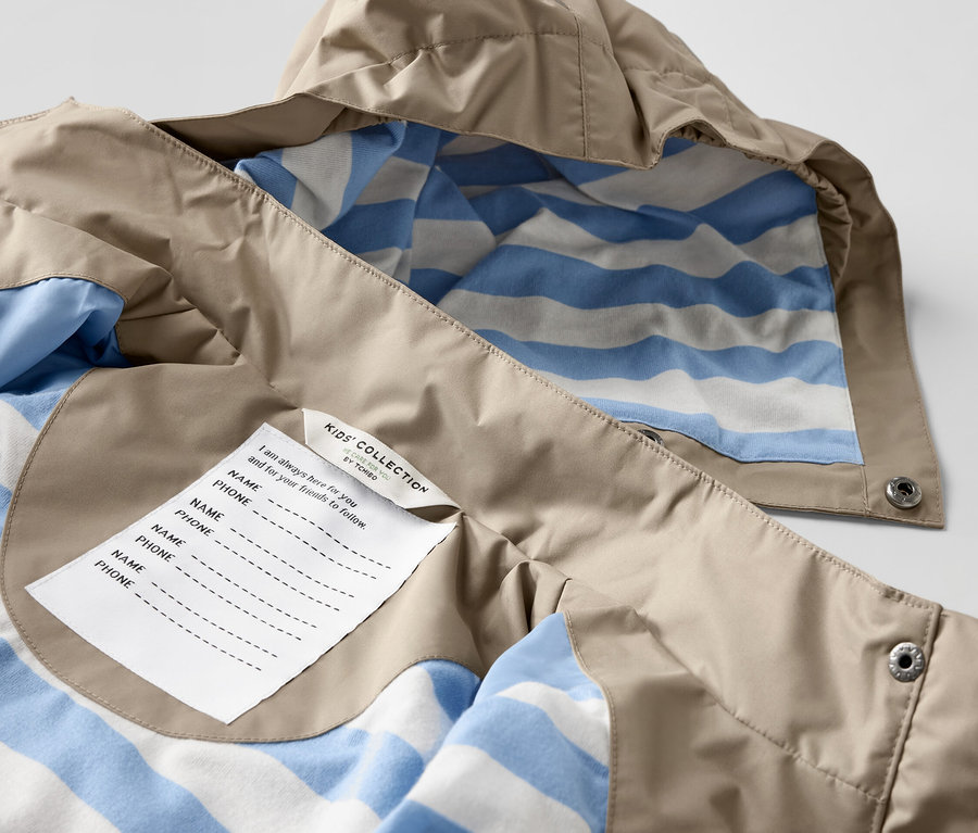 Detail dětské hnědé bundy do deště s modro-bílým pruhovaným vnitřkem.