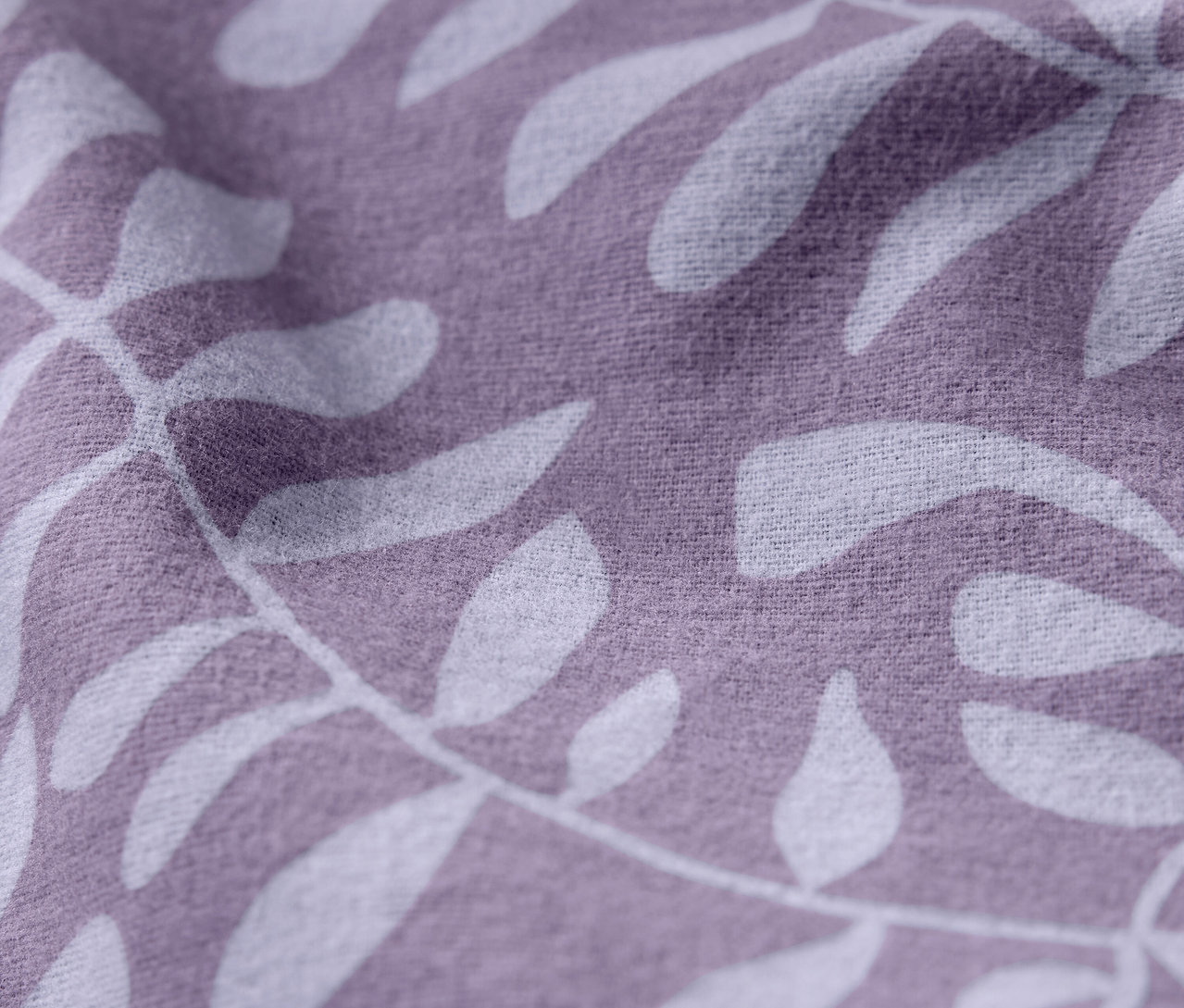 Detailní záběr fialové látky s bílým vzorem listů.