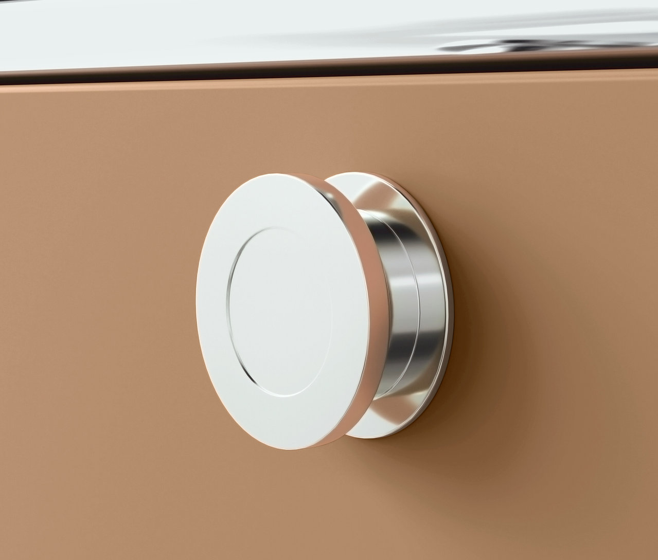 Detail stříbrné kulaté úchytky na hnědé zásuvce.