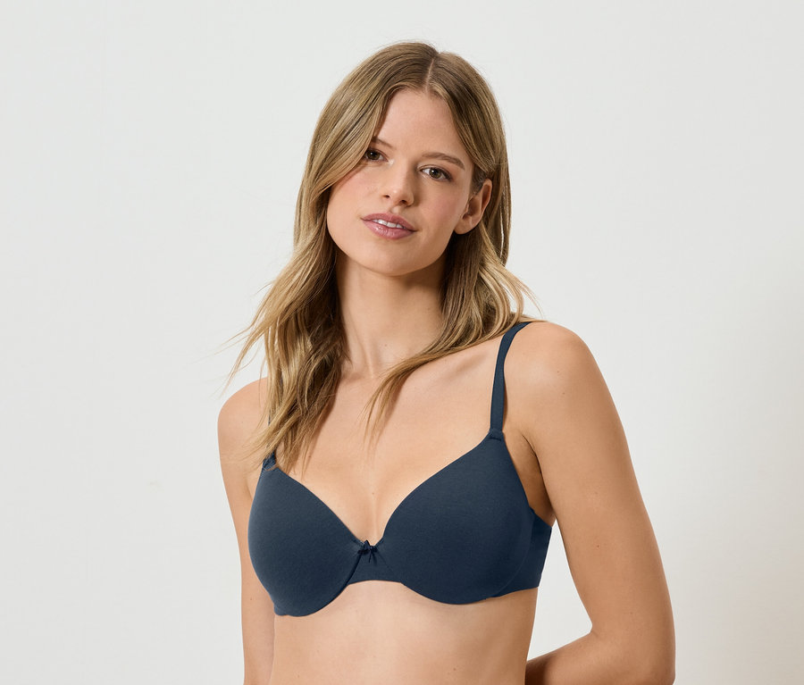 Žena s hnědými vlasy má na sobě tmavě modrou podprsenku.