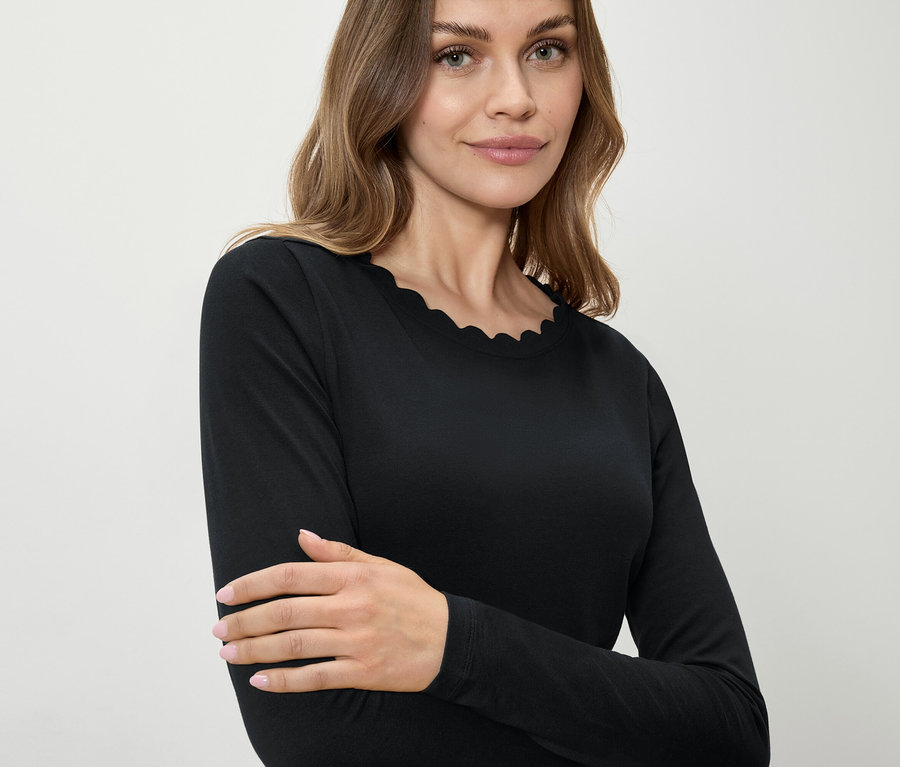 Žena má na sobě černé tričko s dlouhým rukávem a ozdobným lemem.