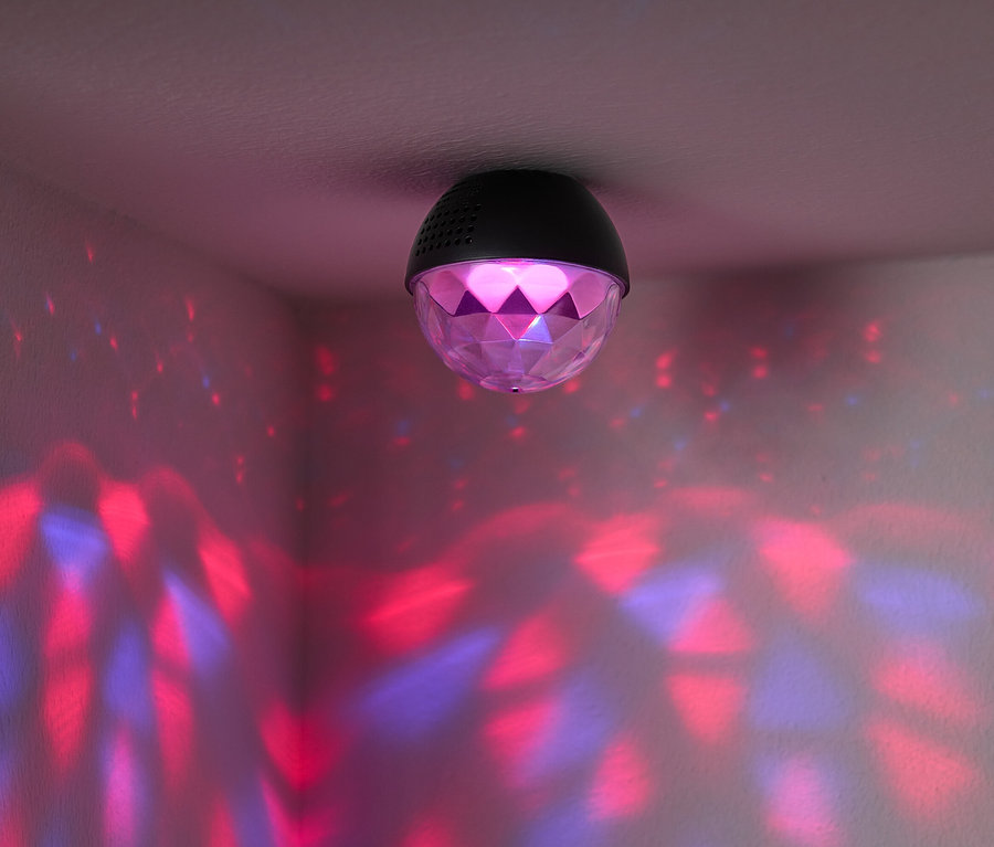 Na stropě je připevněná disco koule, která vrhá na stěny místnosti červená a modrá světla.