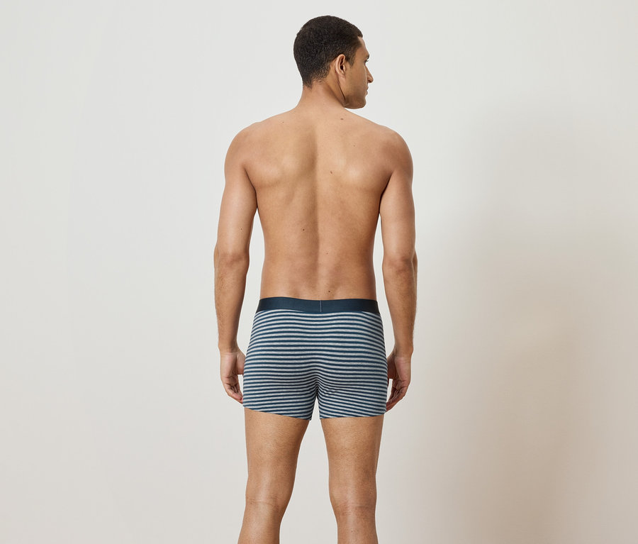 Muž zády ke kameře má na sobě pruhované boxerky.