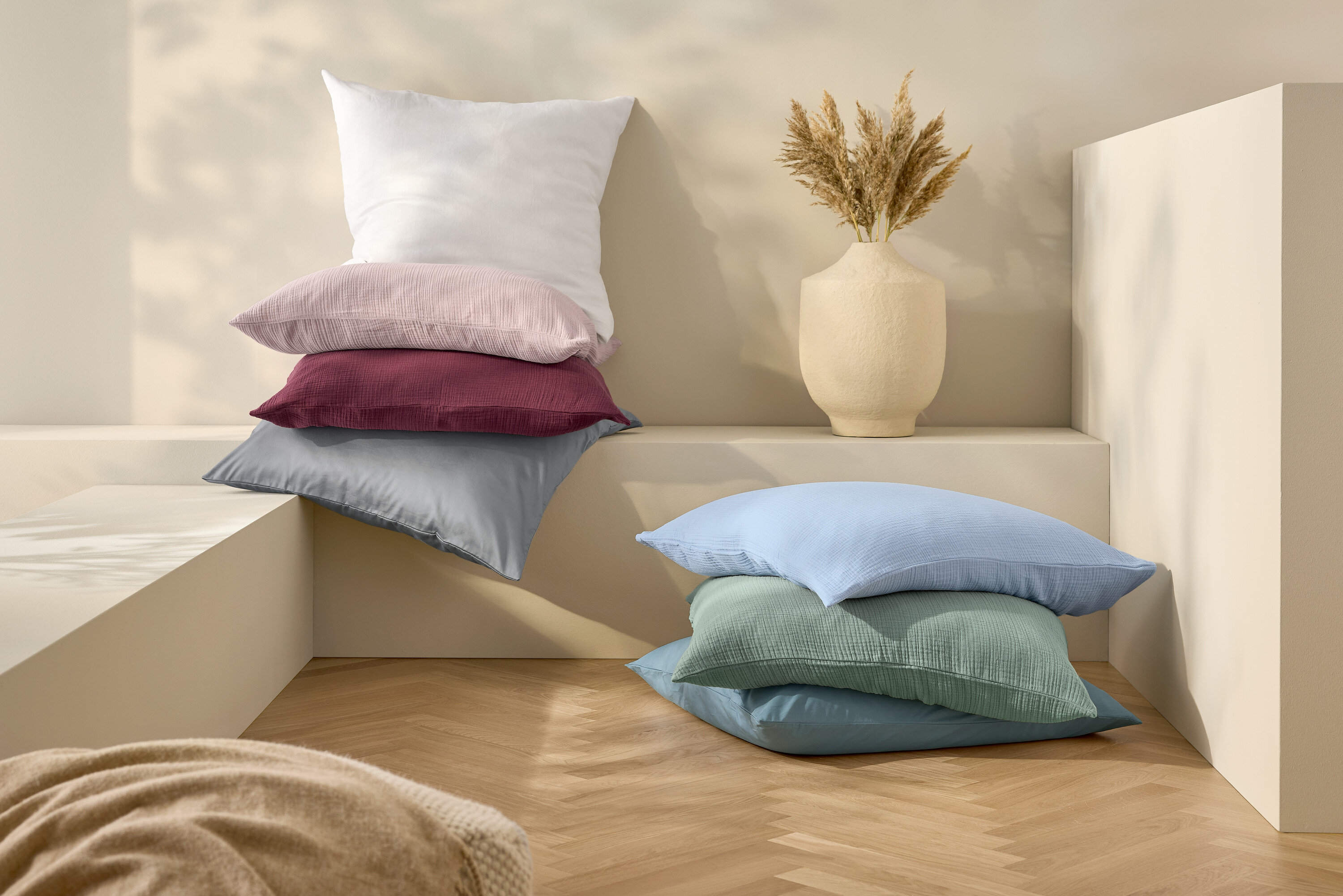 Na sobě naskládané polštáře a leněné povlečení bílé standardní velikosti.