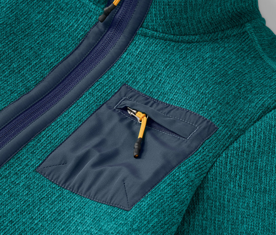 Detail zelenomodré fleecové mikiny s náprsní kapsou na zip.