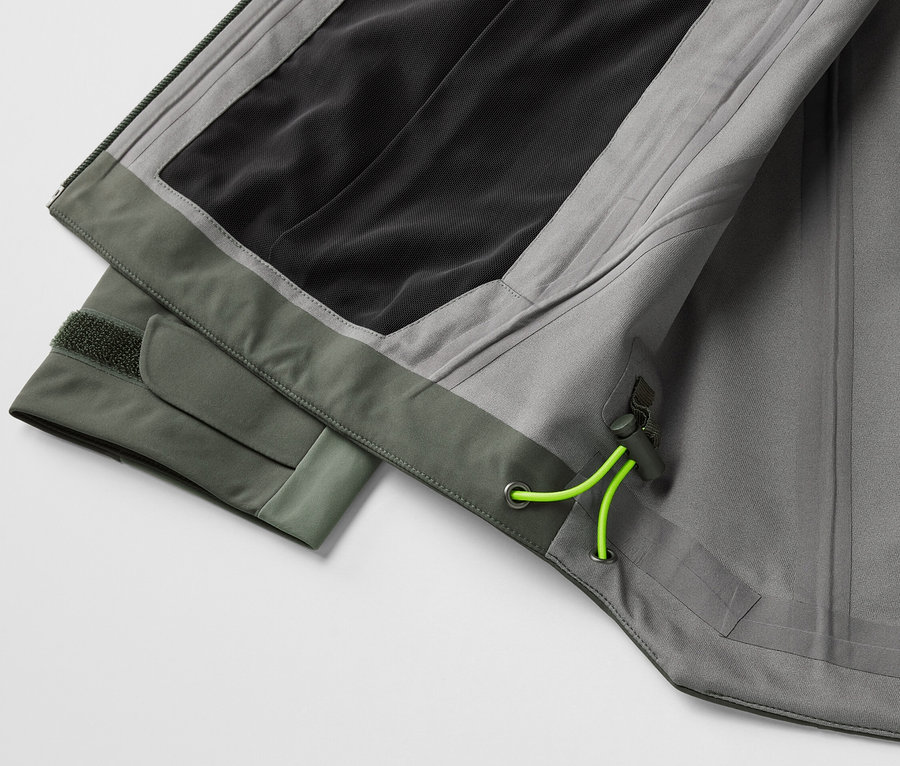 Detail šedé třívrstvé outdoorové bundy se zelenými prvky.