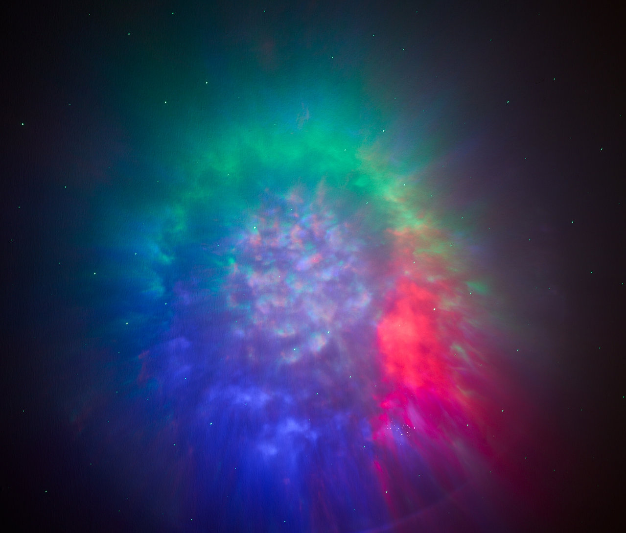 Mlhovina s odstíny zelené, červené a modré barvy na tmavém pozadí.