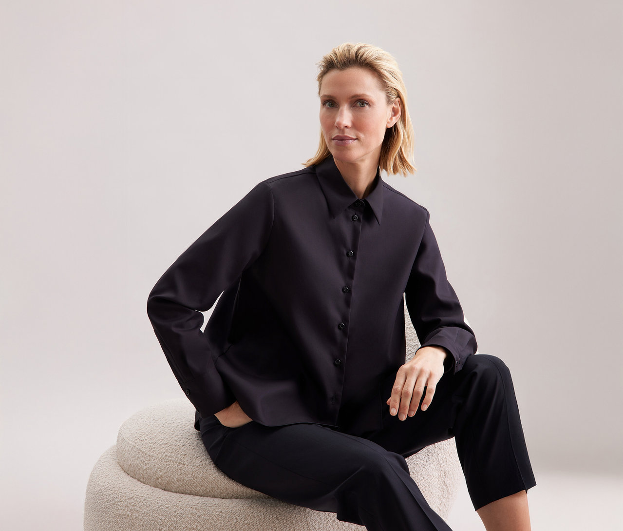 Žena sedí a má na sobě halenku Seidensticker regular.