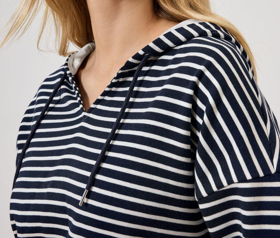 Blondýna má na sobě pruhovanou mikinu s kapucí.