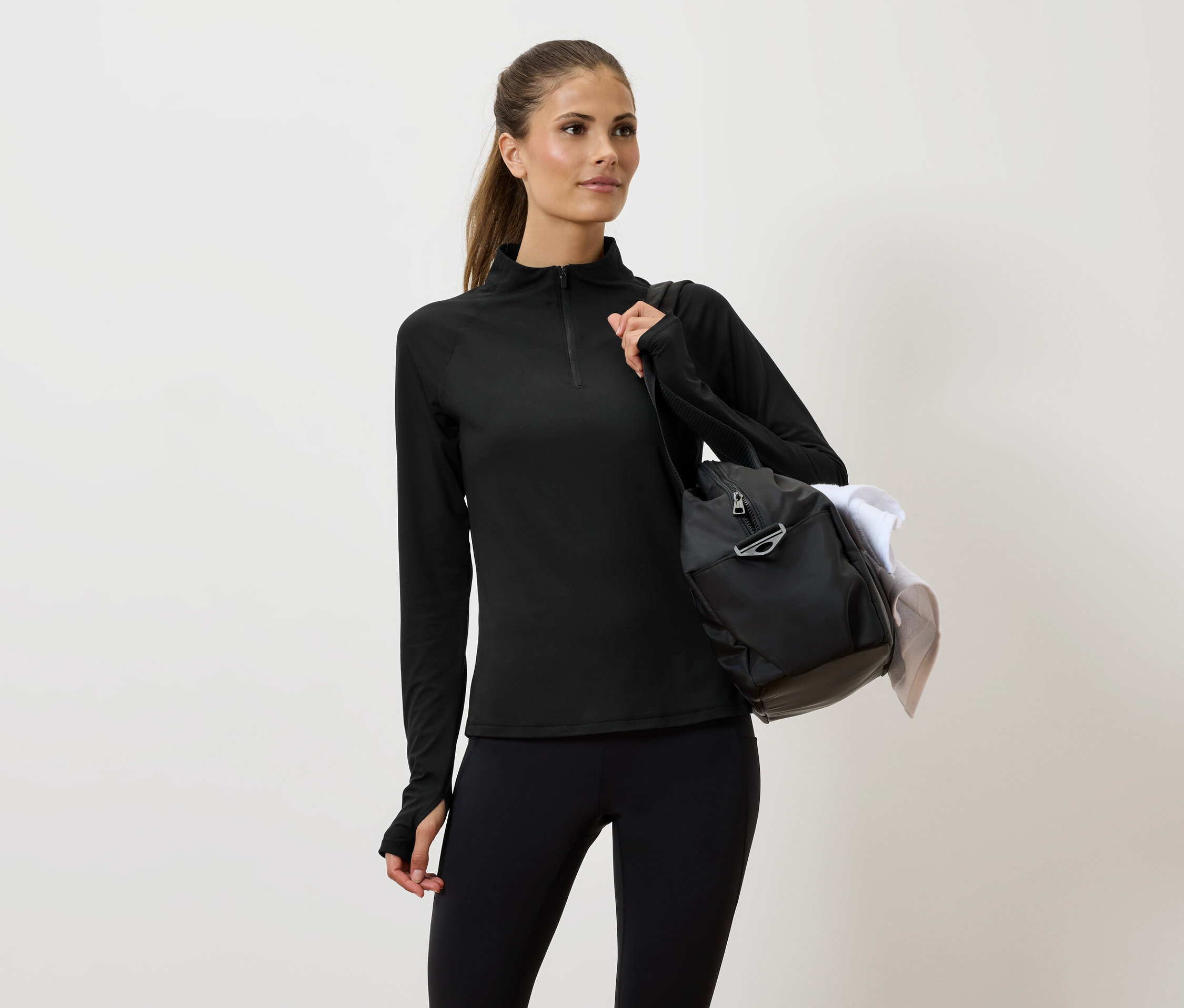 Žena v černém sportovním oblečení s taškou přes rameno.