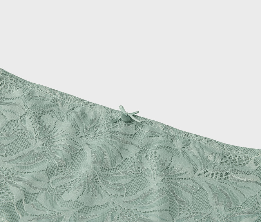 Detail světle zelené krajky s mašličkou.