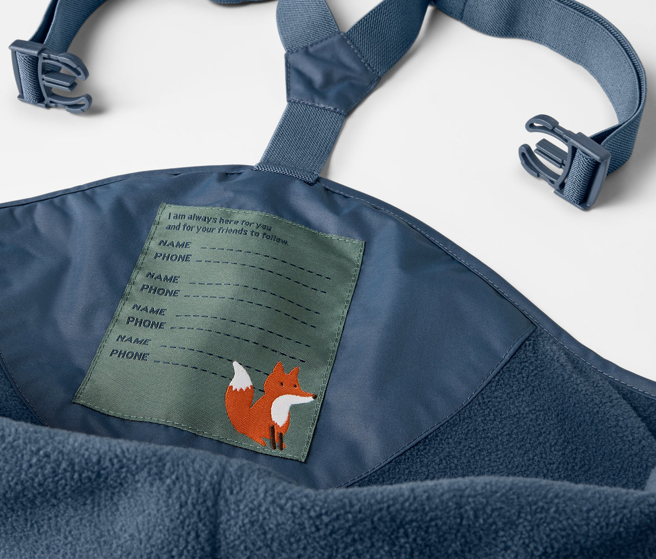 Detail modrých dětských termo kalhot do deště s laclem a štítkem s liškou.