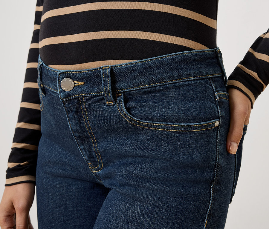 Detailní záběr na ženu v tmavě modrých džínách a pruhovaném topu.